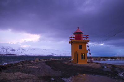 Orange lighthouse at the ocean at night, iceland