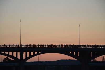 Silhouette people on bridge against sky during sunset