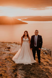 Rear view of bride and bridegroom standing on field