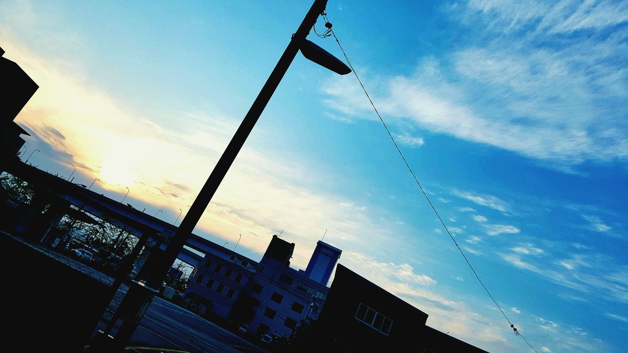 low angle view, sky, cloud - sky, built structure, communication, electricity, technology, fuel and power generation, architecture, power line, blue, cable, silhouette, building exterior, outdoors, power supply, electricity pylon, no people, cloud, lighting equipment