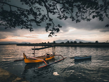 Boat in lake against sky during sunset