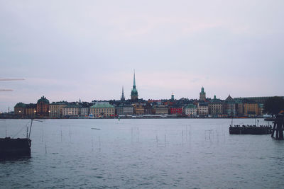 View of buildings by river against sky in city