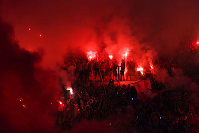 Argentine soccer fans light red flares in the stands of a stadium