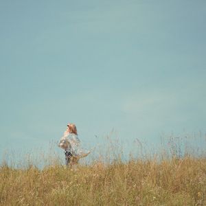 Woman standing on field against clear sky