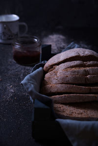 Sliced bread with jam and a cup of hot drink, on a dark background.