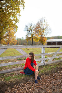 Full length of woman sitting on field during autumn