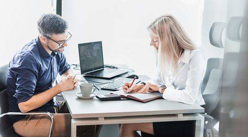 Businesswoman using laptop while sitting on table