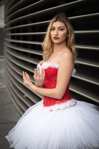 Portrait of young woman standing against curtain