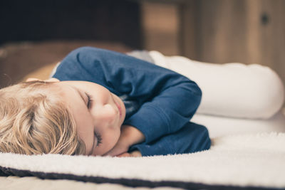 Boy sleeping on bed at home