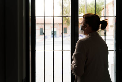 Rear view of man looking through window