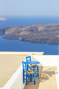 Chairs and table at beach against sky