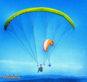 Person paragliding over blue sky