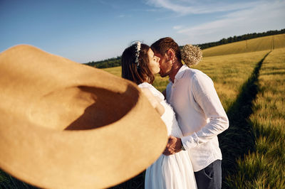 Rear view of woman standing on field against sky