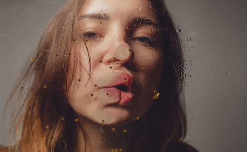 Close-up portrait of woman kissing wet glass with star shape decoration