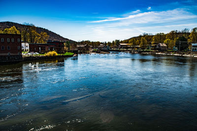 River by buildings in city against sky