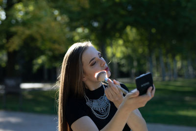 Young woman applying face powder on road