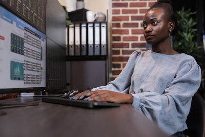 Female trader using desktop pc in office