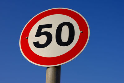 Low angle view of road sign against blue sky