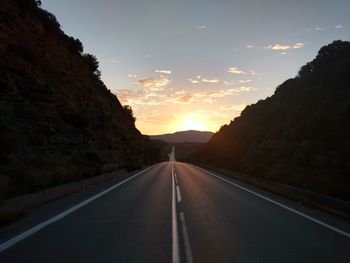 Road amidst mountains against sky during sunset