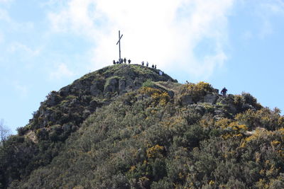 Low angle view of cross on rock against sky