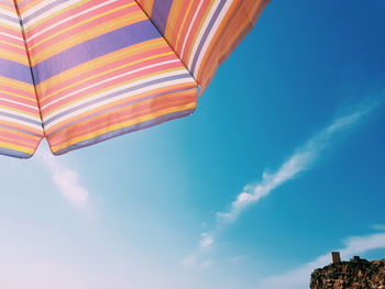 Low angle view of parasol against blue sky during summer