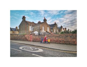 People riding bicycle on road against buildings in city