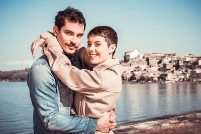 Young couple embraces on the shore of lake bracciano, italy. vintage atmosphere.