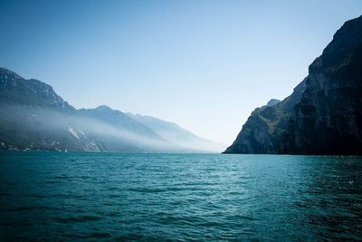 Scenic view of sea and mountains against clear blue sky