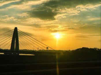 Silhouette suspension bridge against sky during sunset