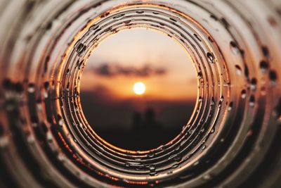 Close-up of glass against sky during sunset