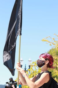 Portrait of woman holding umbrella against clear sky