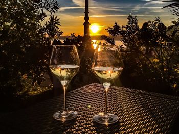 Glass of wine on table against sky during sunset