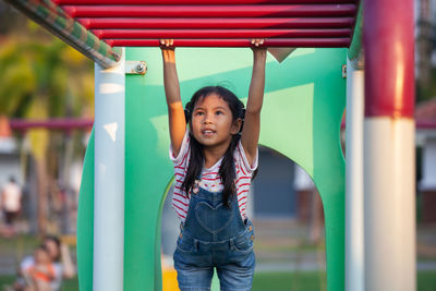 Cute girl hanging on monkey bars at playground