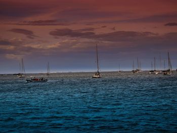 Sailboats sailing in sea against sky during sunset