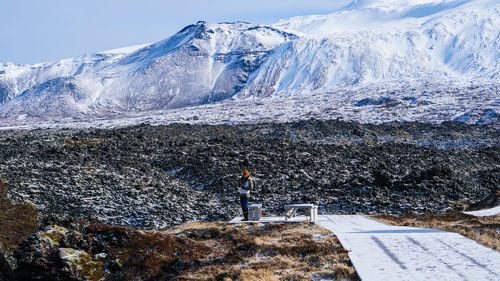 Scenic view of snowcapped mountains with woman standing on land during winter