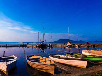 Boats moored in calm blue sea against sky