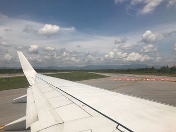 Airplane flying over airport runway against sky