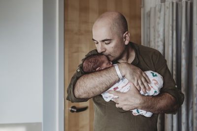 Happy father kissing newborn son wrapped in blankets in hospital