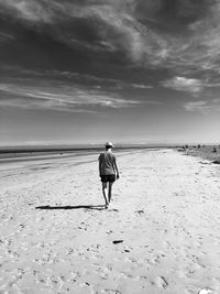 Rear view of man on beach against sky