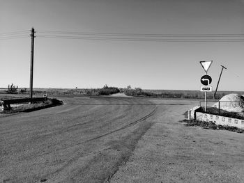 Road sign on street against clear sky