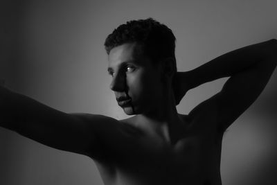 Portrait of shirtless man looking away against gray background