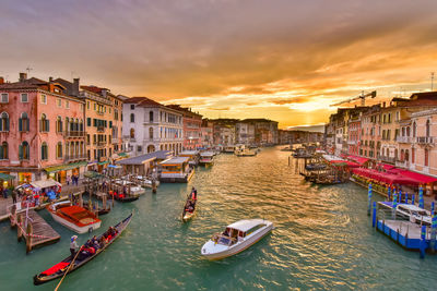 Boats in canal against buildings at sunset