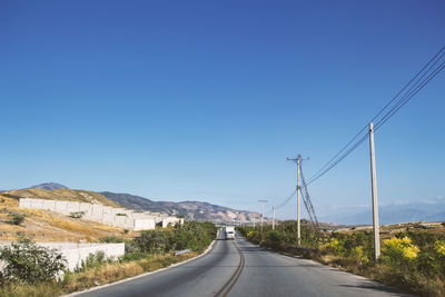 Road by mountain against clear blue sky