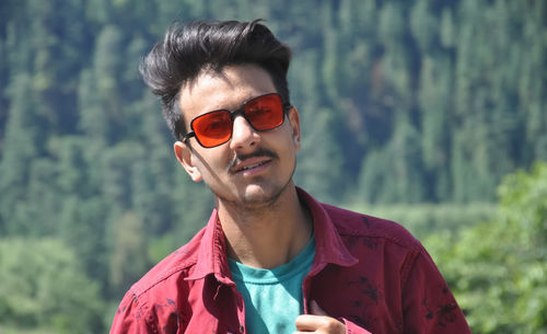 Closeup of a indian young guy posing outdoor with wearing sunglasses with looking at camera
