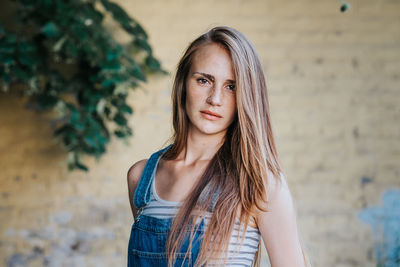 Portrait of young woman standing by wall