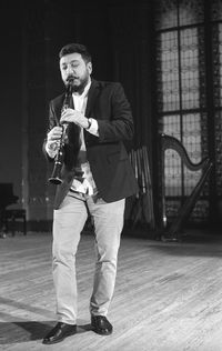 Man playing clarinet while standing at studio