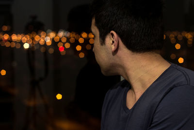 Close-up of young man looking through window at night