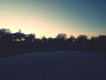 Silhouette trees against clear sky during sunset