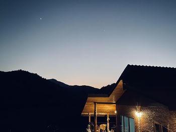 Low angle view of silhouette houses against clear sky at sunset