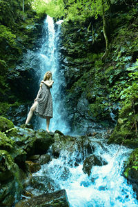 Full length of waterfall on rocks in forest